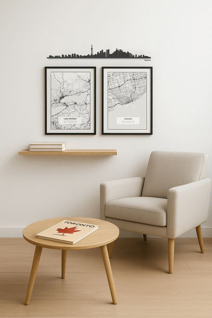 Skyline de Toronto en madera sobre pared blanca, acompañado de mapas enmarcados y mobiliario de estilo nórdico – una propuesta de decoración elegante y personalizada.